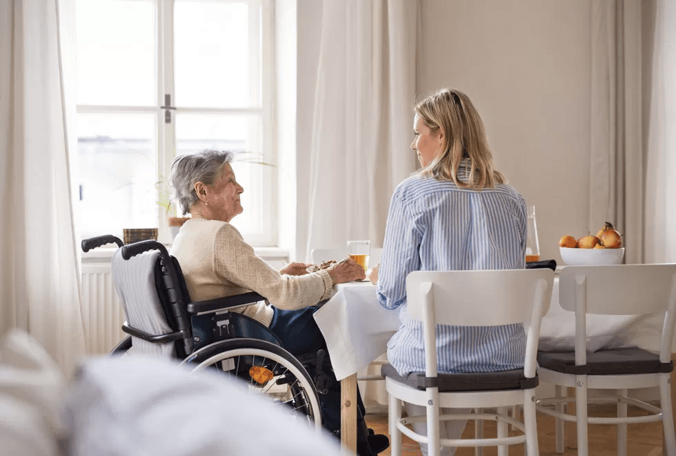 Person in wheelchair sharing breakfast in supported living setting, Topstone Property NDIS.