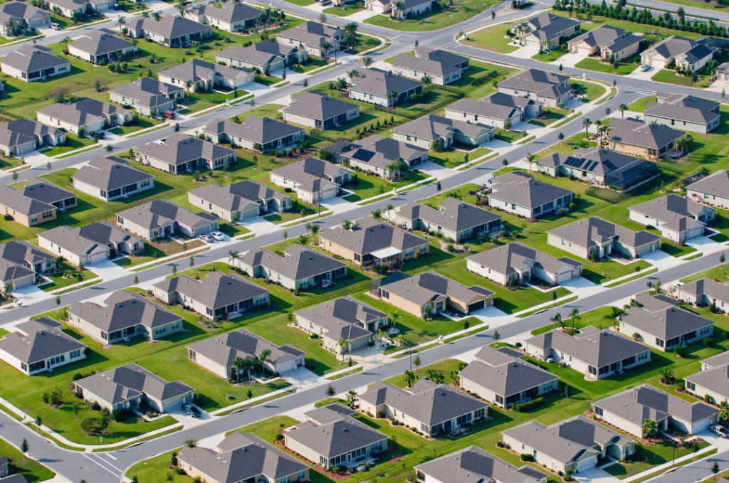 Aerial image of a suburban estate with uniform houses and repetitive layouts, illustrating mass-produced housing.